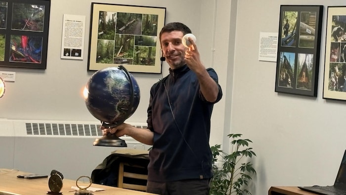 Un homme avec en main   un globe et une boule.
