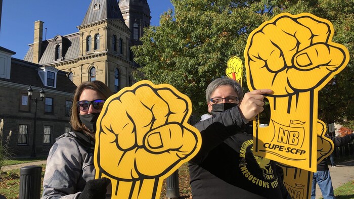 Des manifestantes brandissent des poings jaunes en carton.