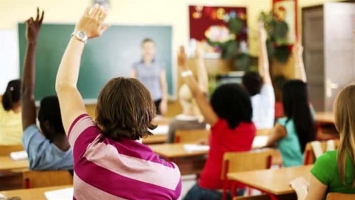 Des enfants lèvent la main dans une salle de classe