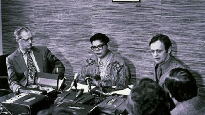 Harry Strom, Harold Cardinal et Jean Chrétien sont assis autour d'une table avec de nombreuses autres personnes.