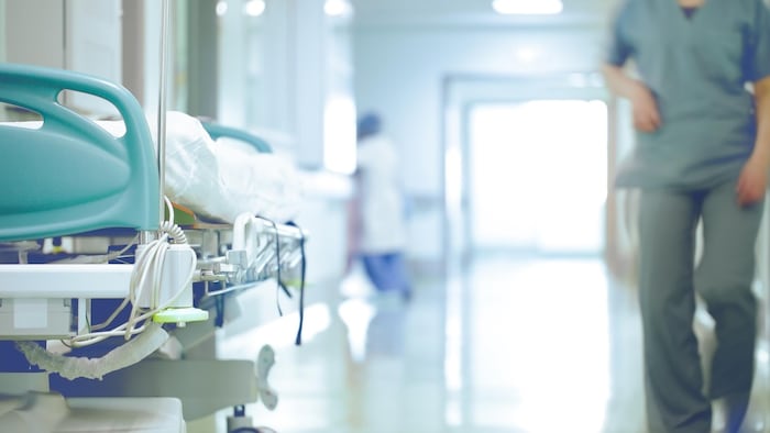 Une infirmière marche d'un pas pressé dans un corridor d'hôpital.