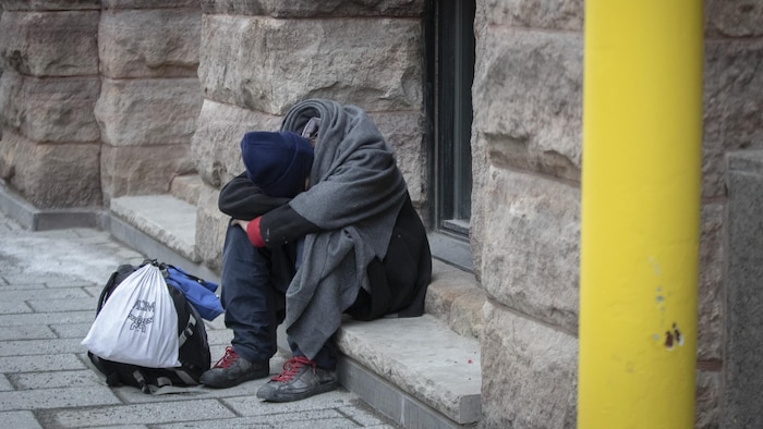 Une personne seule assise devant une fenêtre.