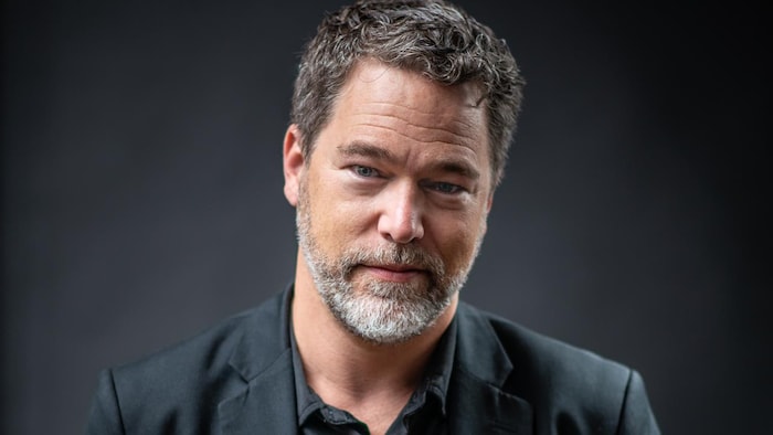 L'auteur a les mains dans les poches de son costume.