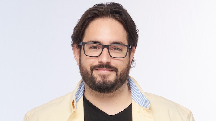 Jérémy Laniel sourit en regardant droit devant lui. Il porte des lunettes.