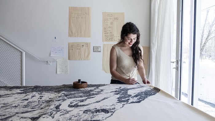 Karine Locatelli en train de peindre une montagne enneigée à l'encre de chine.