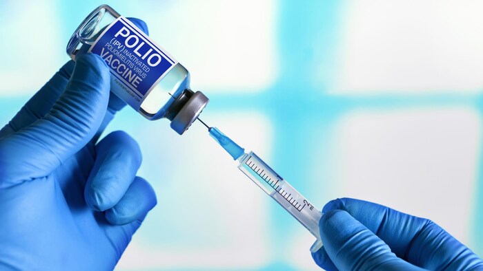 Une personne prélève une dose de vaccin contre la polio à l'aide d'une aiguille dans une fiole.