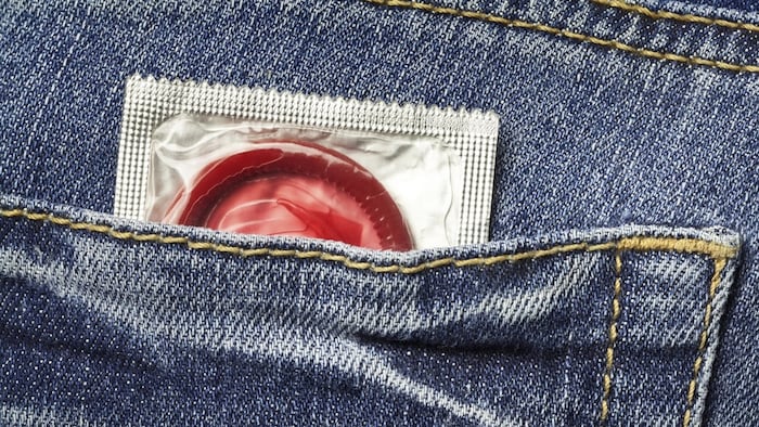 Un condom rouge dans une poche de jeans.