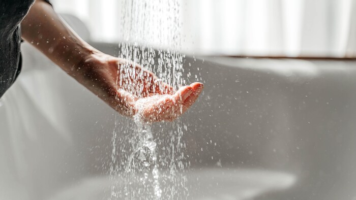 Une personne met sa main sous de l'eau qui coule.