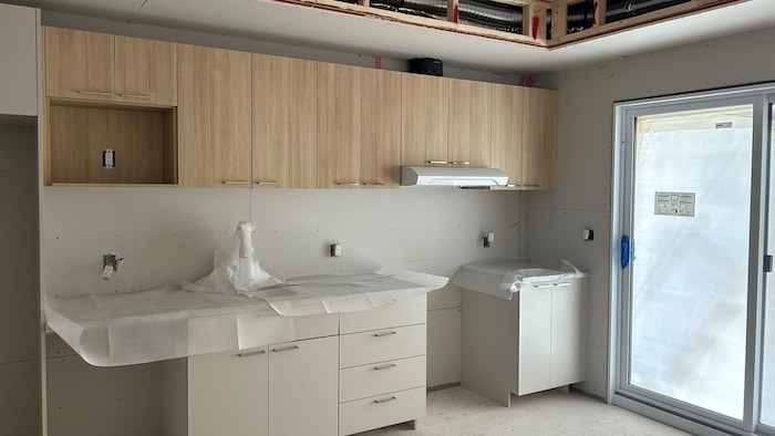 La cuisine est en construction avec des murs encore ouverts en haut et il manque les appareils ménagers.