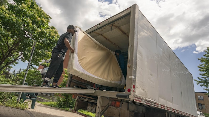 Un homme déplace un matelas dans un camion de déménagement