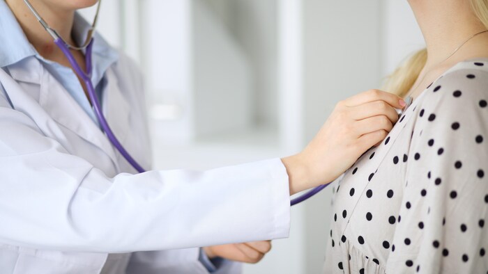 Une médecin examine une patiente avec un stéthoscope.