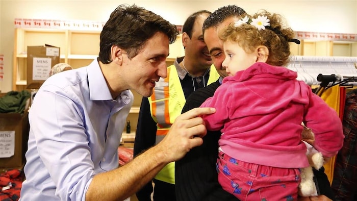 رئيس الحكومة الكندية جوستان ترودو مستقبلاً لاجئين سوريين قادمين من بيروت في مطار بيرسون الدولي في تورونتو في 11 كانون الأول (ديسمبر) 2015.