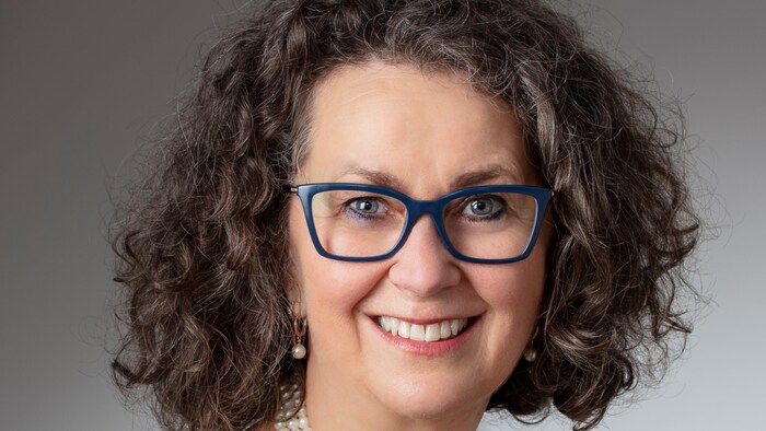 La femme souriante, portant des lunettes.
