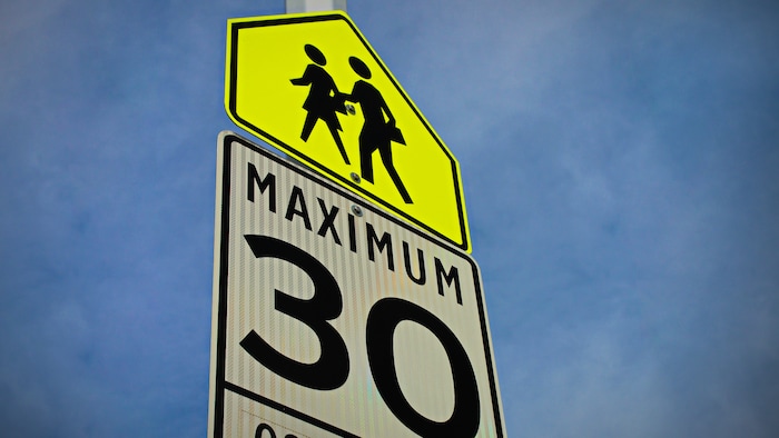 Panneau de signalisation indiquant une limite de vitesse de 30 km/h dans une zone scolaire