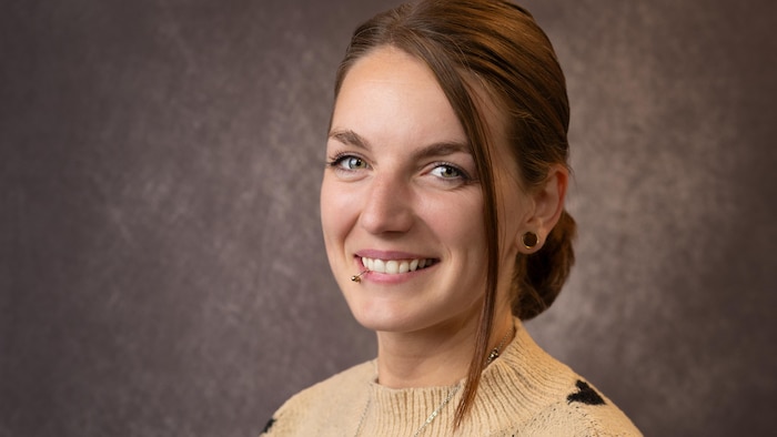 Liza Mclaughlin est assise et sourit, tournée de trois quarts vers l'objectif.
