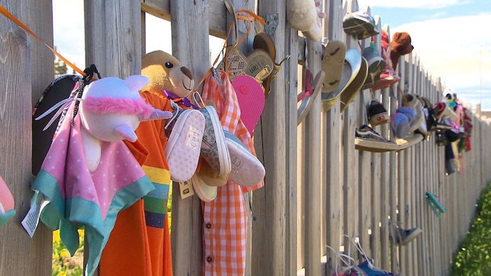 Peluches et souliers accrochés à une clôture.
