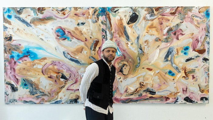 Manuel Mathieu devant une toile d'art contemporain colorée.