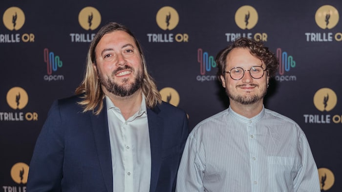 Deux hommes – l'un avec les cheveux longs et l'autre avec des lunettes – posent.