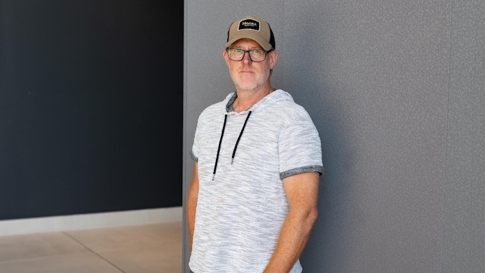 Il porte une casquette et un chandail à capuchon. 