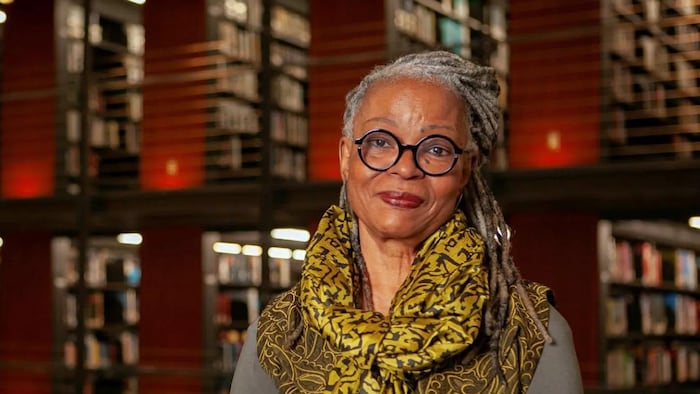 Marie-Célie Agnant est dans une bibliothèque avec des rayonnages remplis de livres.