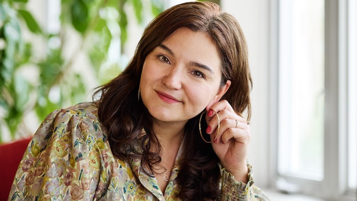 Marie-Noëlle Morency est assise et se tient l'oreille, la tête penchée.