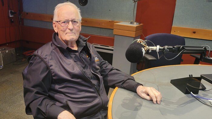 Un homme prend la pose pour la photo dans un studio de radio.