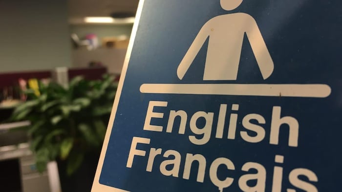 Affichette de bureau qui indique un service dans les deux langues officielles, le français et l'anglais.
