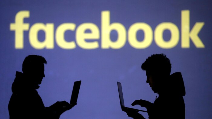 Des silhouettes de personnes se tiennent debout devant un logo Facebook.
