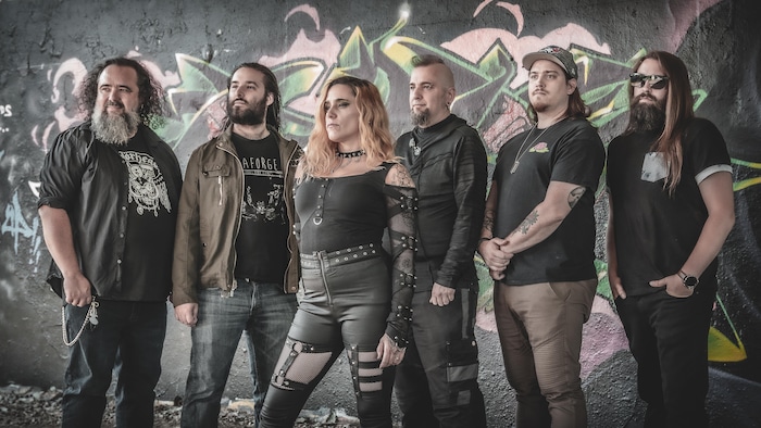 Les six membres de Règlement 17 posent devant un mur couvert de graffitis.
