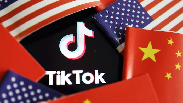 Le logo de TikTok est coincé entre des drapeaux américains et chinois.