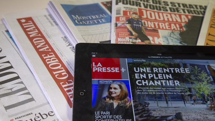 Journaux divers : une tablette affichant La Presse+, par-dessus le National Post, The Globe and Mail, Le Devoir, The Gazette et Le Journal de Montréal.