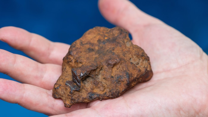 Gros plan d'une météorite de fer dans la paume d'une main.