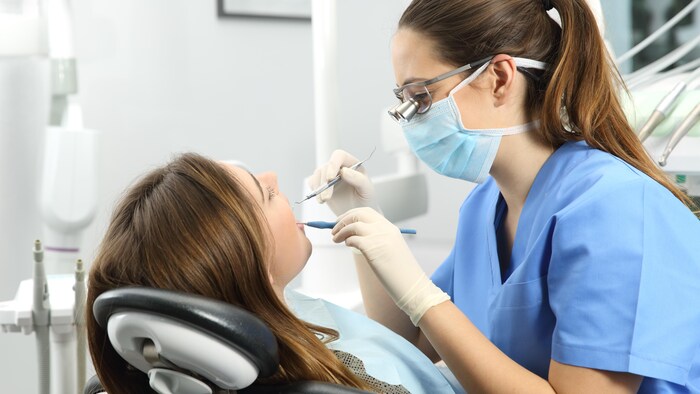 Une hygiéniste dentaire fait l'évaluation d'une patiente.