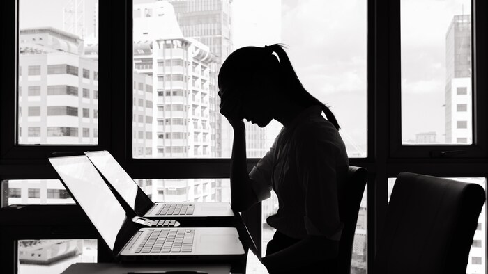 Profil d'une femme déprimée à son clavier d'ordinateur.