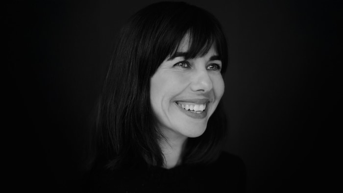 Portrait noir et blanc de Brigitte Vaillancourt, souriante, qui regarde vers le côté.