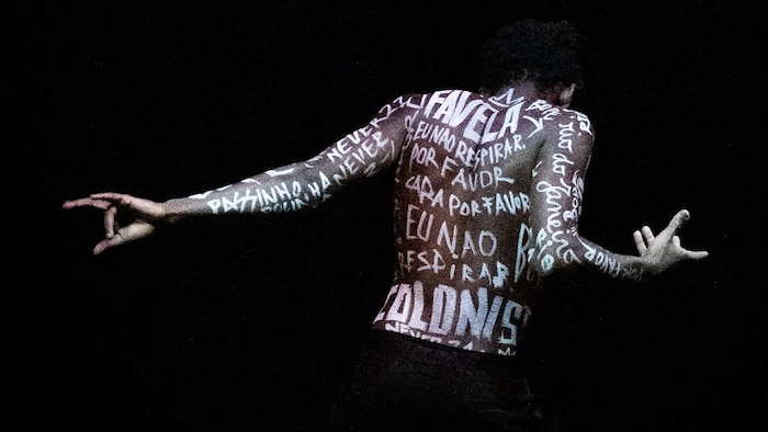 رجل أسود البشرة يرقص وقد كتب على جسمه العديد من أسماء الأشخاص.