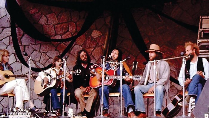 Robert Paquette participe à un atelier musical avec plusieurs invités sur l'estrade.