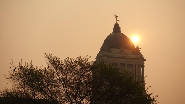 Le Palais Législatif du Manitoba au lever du soleil sous la fumée des feux de forêts le dimanche 12 mai 2024.  