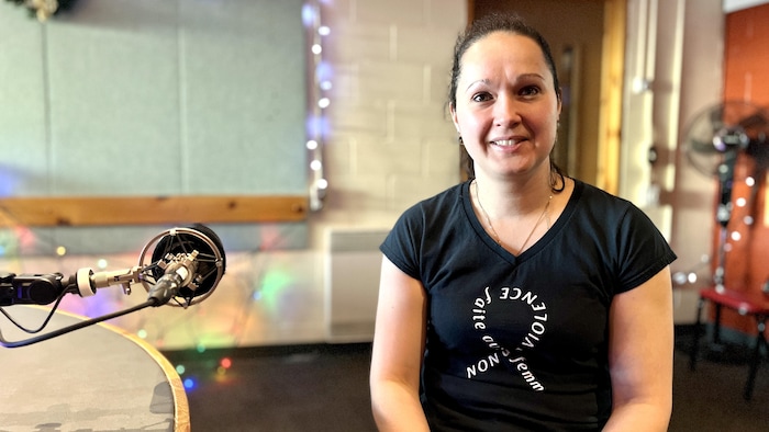 Une femme en studio avec un t-shirt où on peut lire Non à la violence faite aux femmes.
