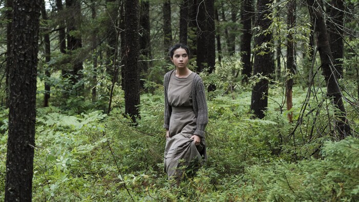 Une jeune femme marche seule en forêt.