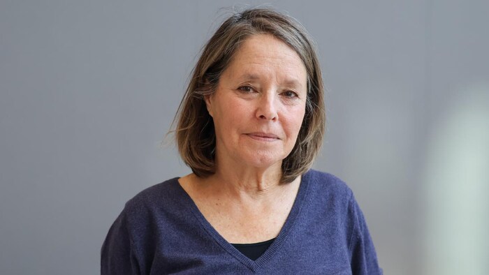 Michèle Ouimet est devant un mur gris dans l'atrium de Radio-Canada.