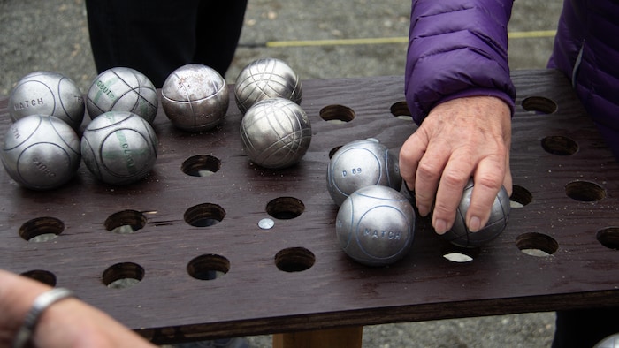 Une main sur une boule de pétanque.