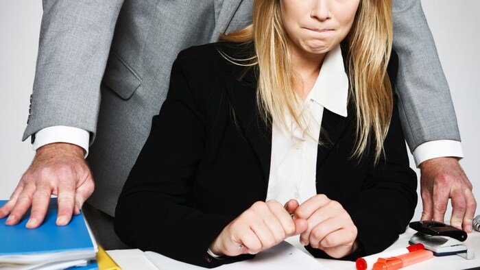un homme se tient debout derrière une femme qui est assise à un bureau