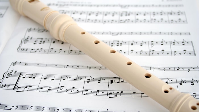 Une flûte à bec déposée sur des feuilles de musique.