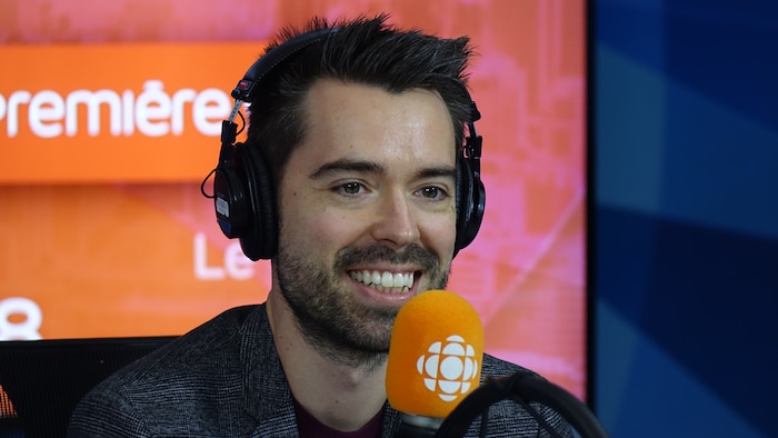 Olivier Bernard derrière un micro dans un studio radio de Radio-Canada.