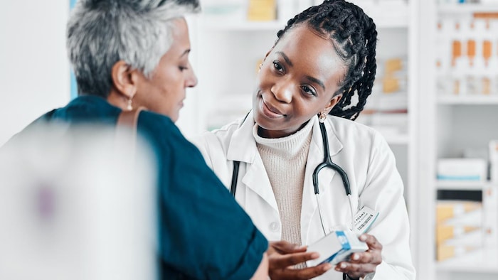 Une pharmacienne avec une patiente lui parle d'un médicament. 