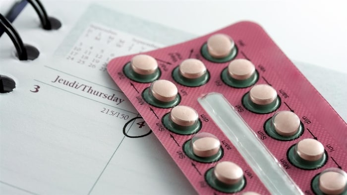Des pilules contraceptives dans leur emballage déposé sur un agenda ouvert.