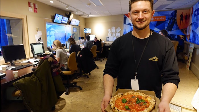 Mirko D'Agata tenant une pizza dans un studio de Radio-Canada.
