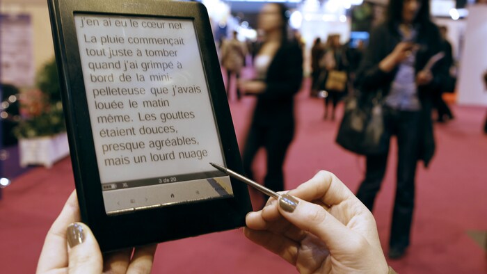 Une femme lit un livre sur une tablette électronique.