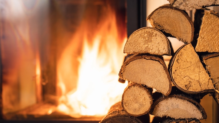 Une pile de bois de chauffage devant un poêle.